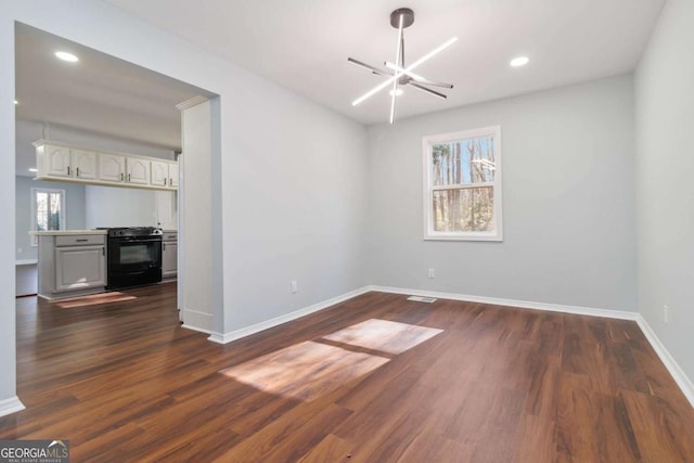 empty room featuring dark wood-type flooring and an inviting chandelier