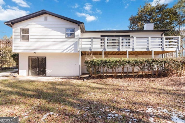 rear view of house with a lawn and a wooden deck