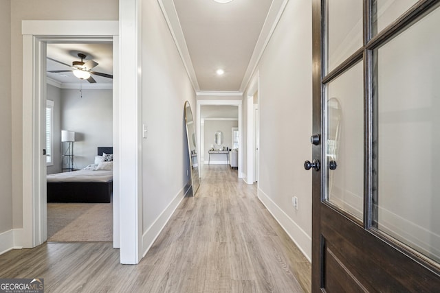 hallway featuring ornamental molding and light wood-type flooring