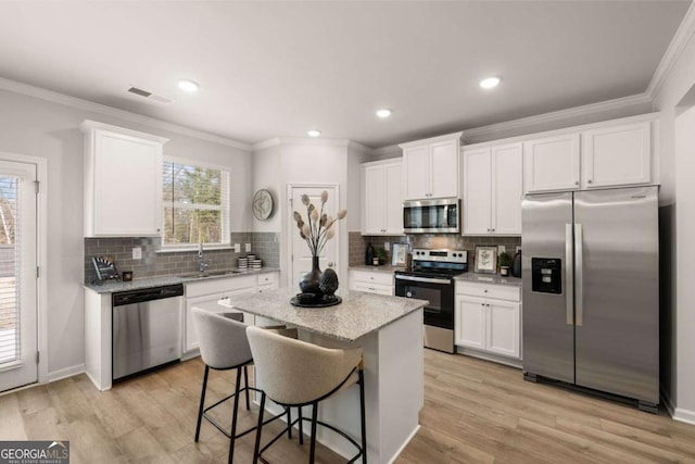 kitchen featuring sink, white cabinets, a breakfast bar area, a kitchen island, and appliances with stainless steel finishes