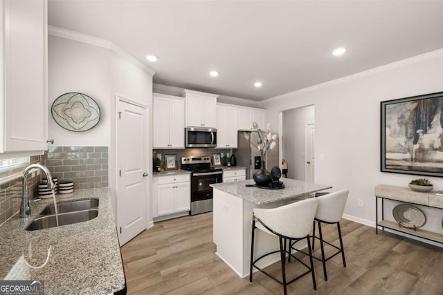 kitchen featuring stainless steel appliances, white cabinetry, sink, and light stone countertops