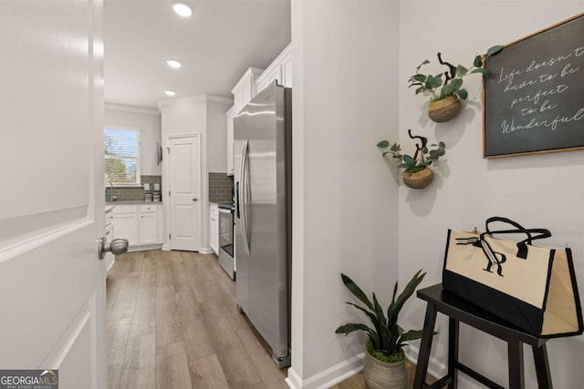 corridor with sink, crown molding, and light hardwood / wood-style flooring