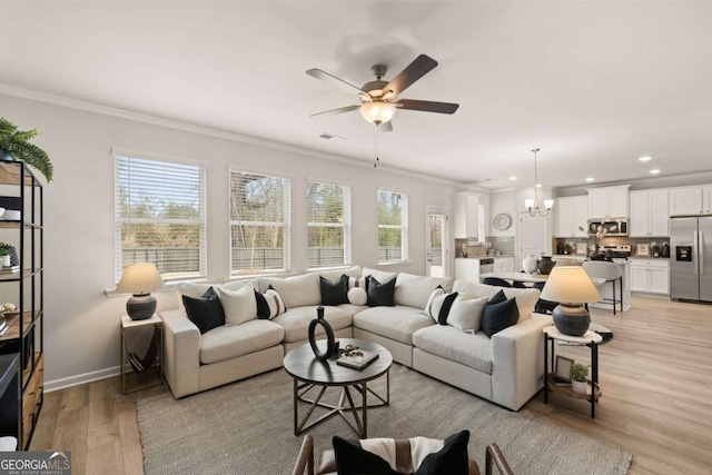 living room with light hardwood / wood-style floors, ornamental molding, and ceiling fan with notable chandelier