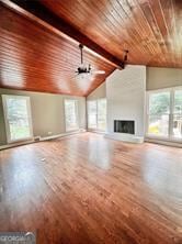 unfurnished living room with a fireplace, wooden ceiling, vaulted ceiling with beams, and a healthy amount of sunlight