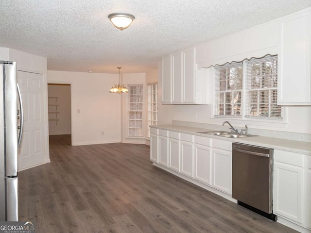 kitchen featuring stainless steel appliances, white cabinetry, sink, and pendant lighting