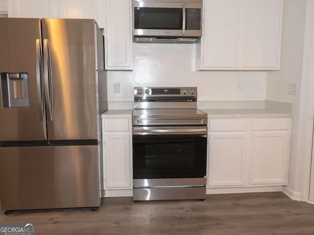 kitchen with white cabinets, appliances with stainless steel finishes, and dark hardwood / wood-style flooring