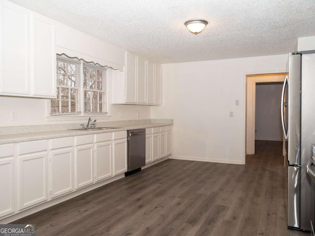 kitchen featuring stainless steel appliances, white cabinetry, sink, and a textured ceiling