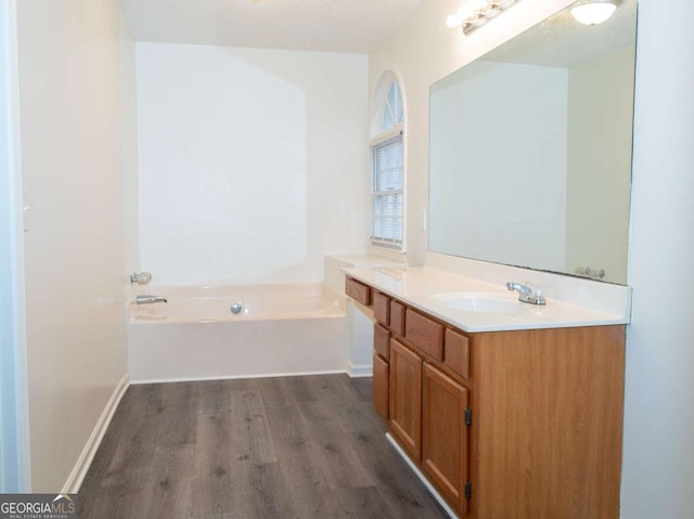 bathroom with a bathing tub, a textured ceiling, hardwood / wood-style flooring, and vanity