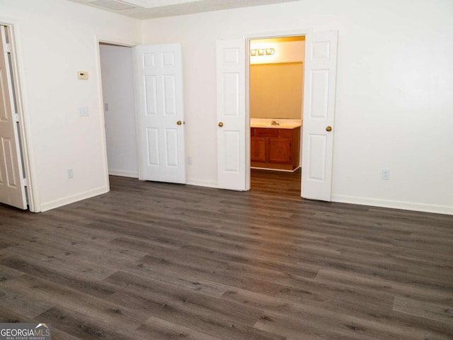 unfurnished bedroom featuring dark hardwood / wood-style flooring and connected bathroom