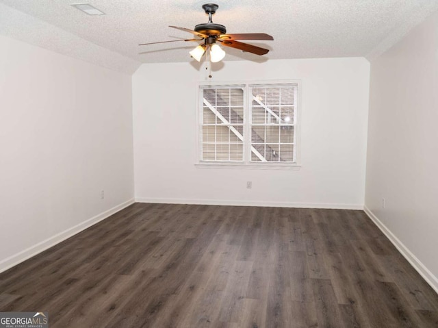 empty room with a textured ceiling, ceiling fan, vaulted ceiling, and dark hardwood / wood-style floors