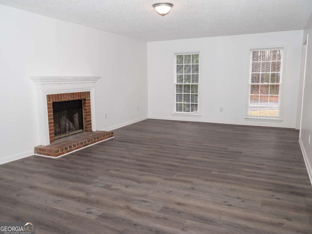 unfurnished living room with a fireplace, a textured ceiling, and dark hardwood / wood-style flooring