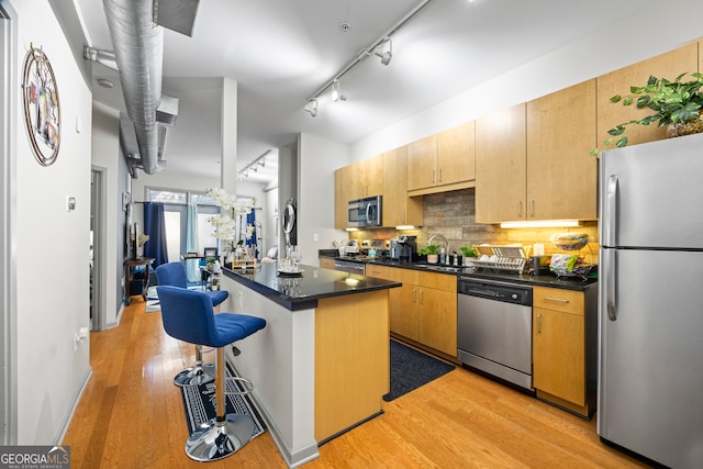 kitchen featuring light hardwood / wood-style flooring, a center island, rail lighting, appliances with stainless steel finishes, and sink