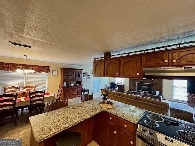 kitchen featuring a textured ceiling, hanging light fixtures, light stone countertops, stainless steel range with electric stovetop, and a notable chandelier