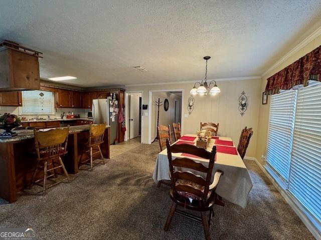 carpeted dining area with a textured ceiling, ornamental molding, and a notable chandelier