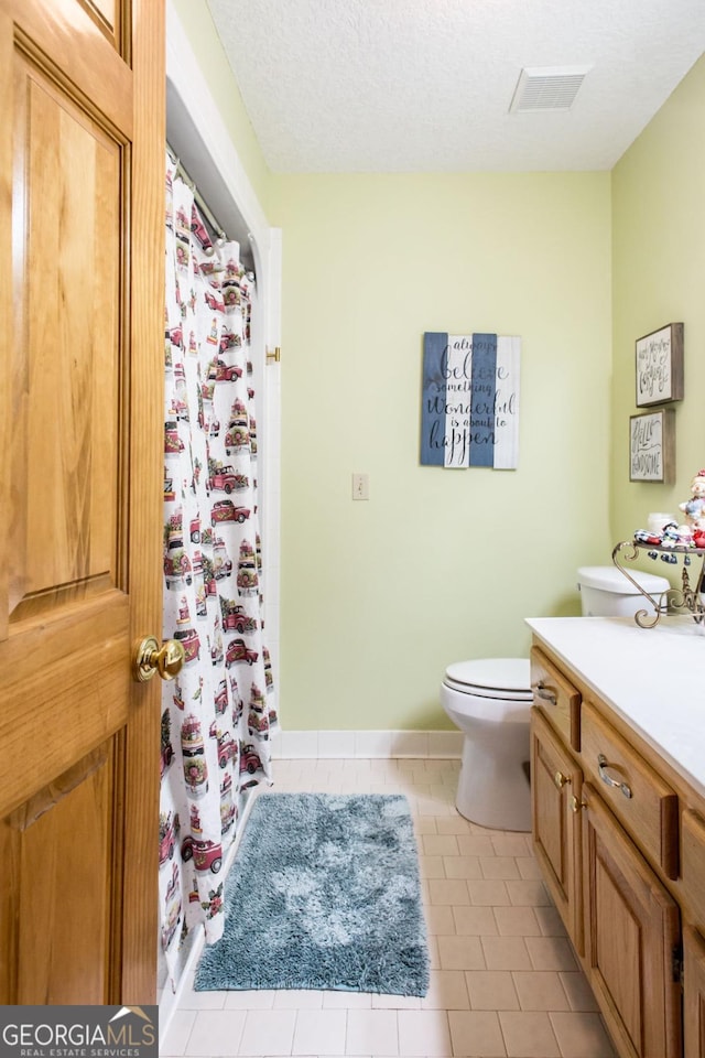 bathroom with vanity, toilet, tile patterned flooring, and a textured ceiling