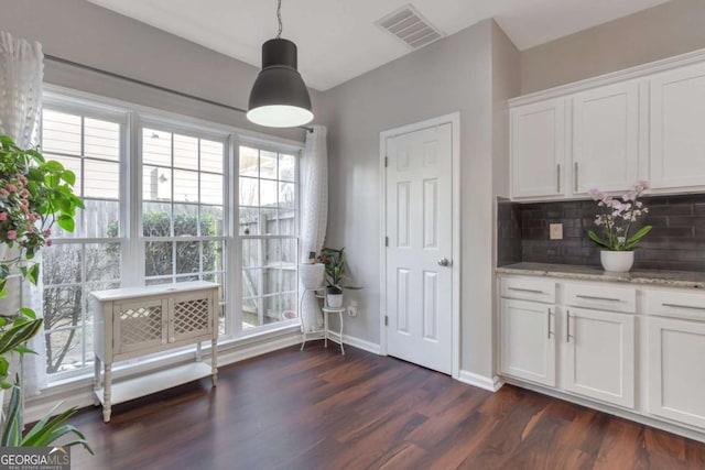 kitchen featuring hanging light fixtures, light stone countertops, dark wood-type flooring, decorative backsplash, and white cabinetry