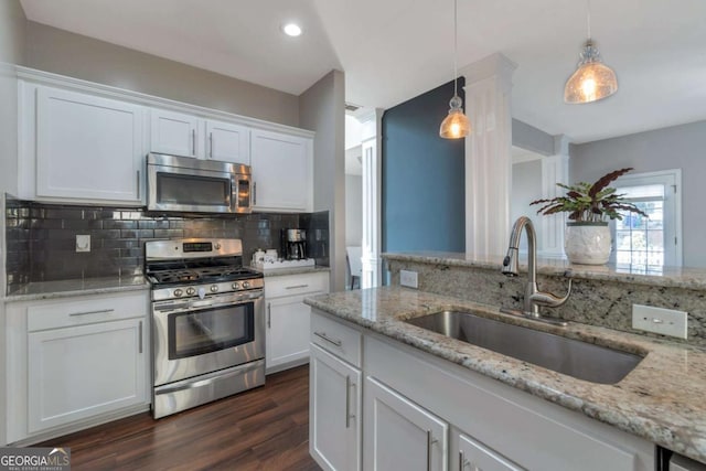 kitchen with appliances with stainless steel finishes, white cabinets, decorative light fixtures, and sink