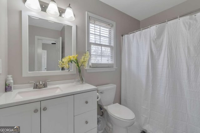 bathroom with toilet, vanity, and walk in shower