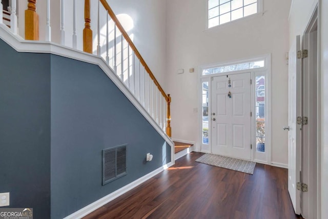 entryway featuring a towering ceiling, dark wood-type flooring, and a wealth of natural light