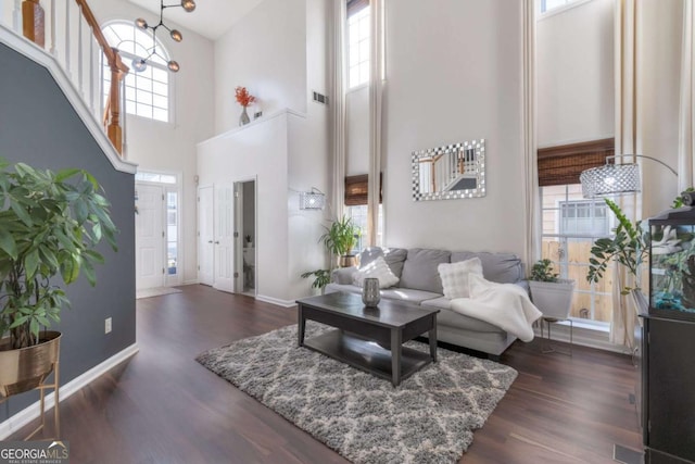 living room with a high ceiling, dark hardwood / wood-style flooring, and plenty of natural light