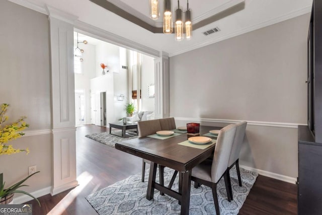 dining space featuring dark hardwood / wood-style flooring, a raised ceiling, ornamental molding, and a notable chandelier