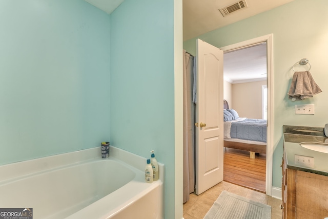 bathroom featuring a bath, tile patterned flooring, ornamental molding, and vanity