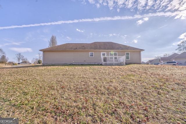 back of property with a deck and a lawn