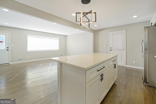 kitchen with a center island, stainless steel fridge, pendant lighting, and white cabinetry