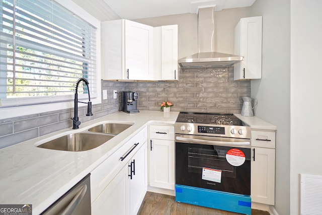 kitchen featuring white cabinets, appliances with stainless steel finishes, wall chimney exhaust hood, and backsplash