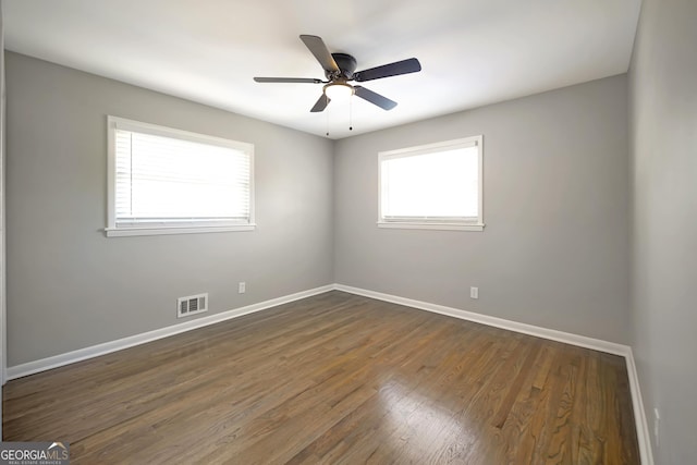 empty room with ceiling fan and dark hardwood / wood-style flooring