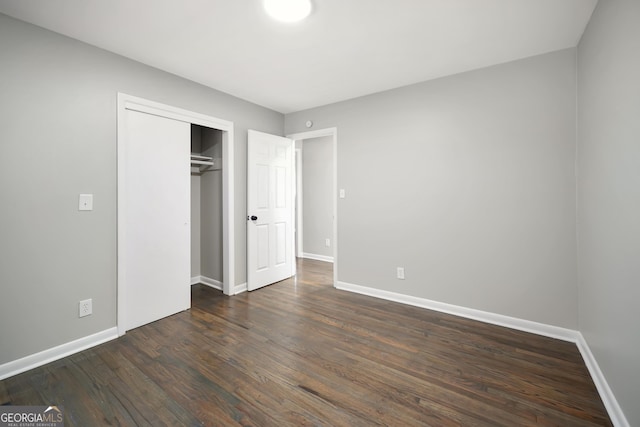 unfurnished bedroom with a closet and dark wood-type flooring