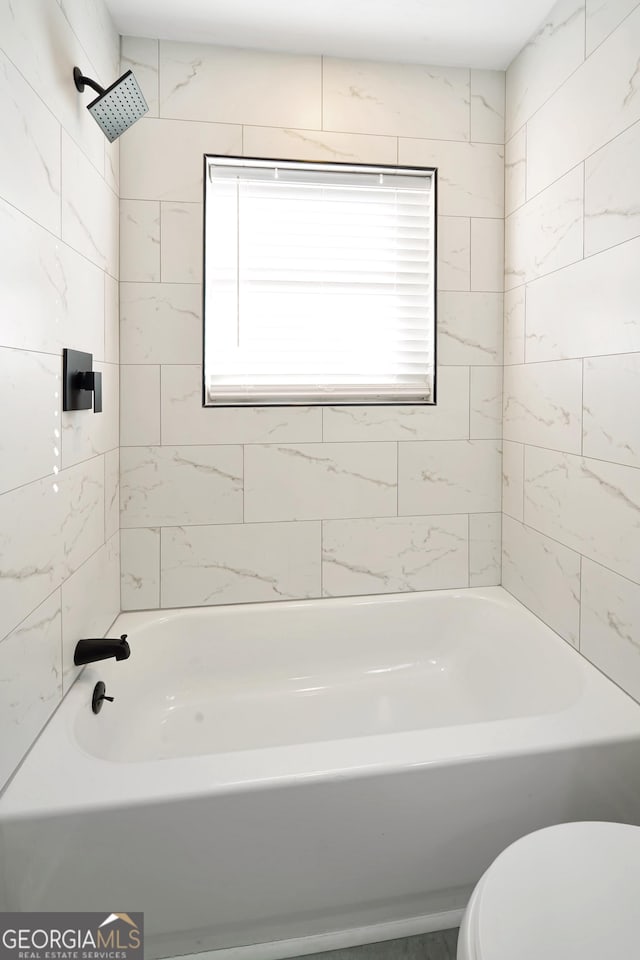 bathroom featuring toilet and tiled shower / bath