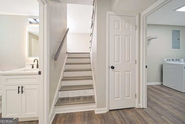 stairway featuring electric panel, sink, and wood-type flooring