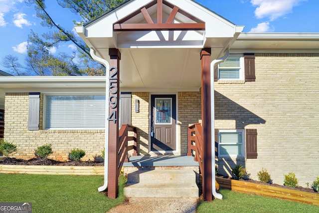 view of exterior entry featuring a lawn