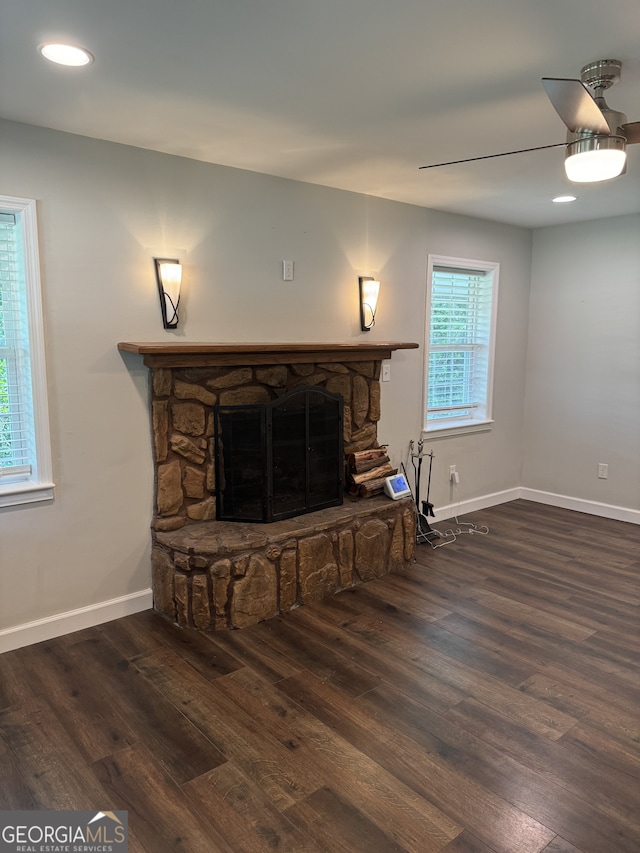 living room with ceiling fan, a healthy amount of sunlight, dark hardwood / wood-style floors, and a fireplace