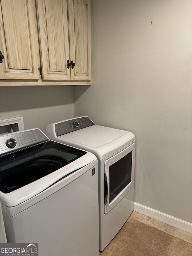 clothes washing area featuring separate washer and dryer and cabinets