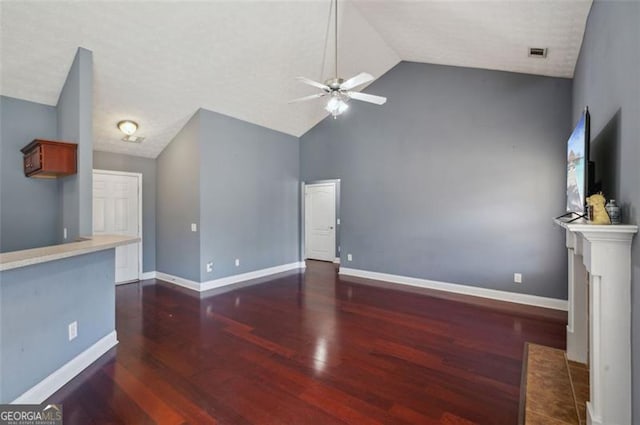 unfurnished living room with vaulted ceiling, ceiling fan, dark hardwood / wood-style flooring, a brick fireplace, and a textured ceiling