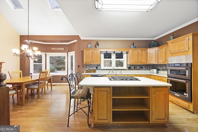 kitchen featuring a center island, multiple ovens, a notable chandelier, and a skylight