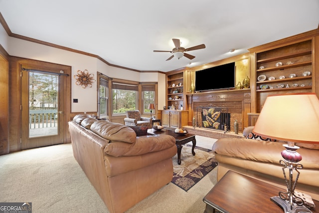 carpeted living room featuring ceiling fan, ornamental molding, a fireplace, and built in features