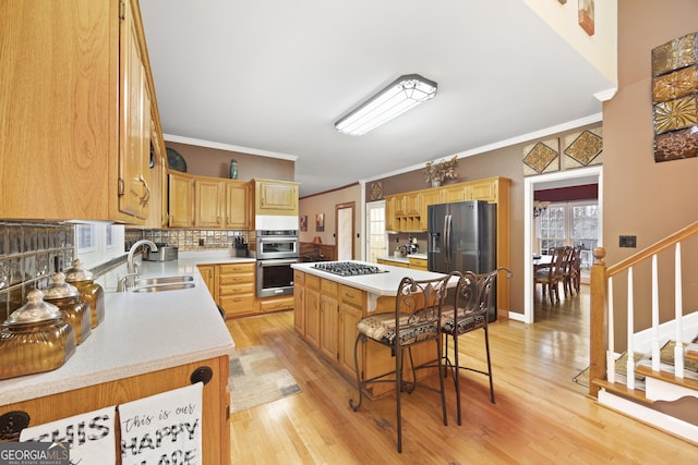 kitchen with sink, a breakfast bar area, appliances with stainless steel finishes, a center island, and ornamental molding