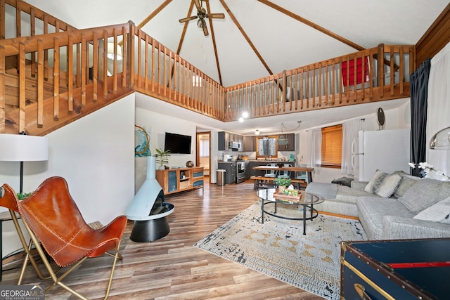 living room with a towering ceiling, ceiling fan, and hardwood / wood-style flooring