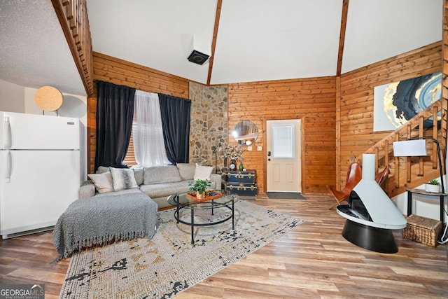 living room with hardwood / wood-style flooring, high vaulted ceiling, and wooden walls