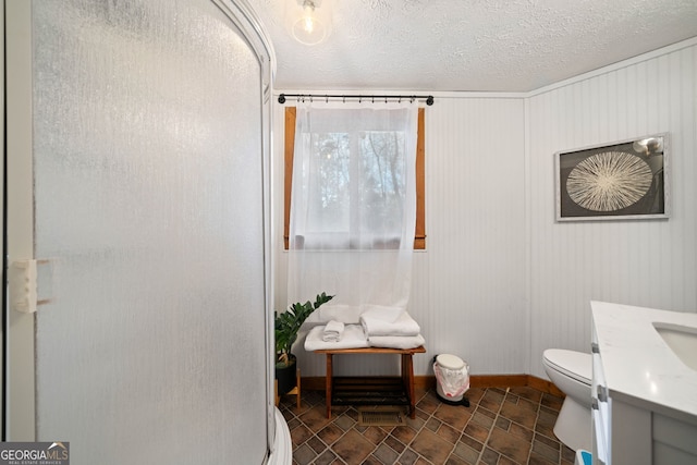 bathroom featuring toilet, a textured ceiling, a shower with door, and vanity