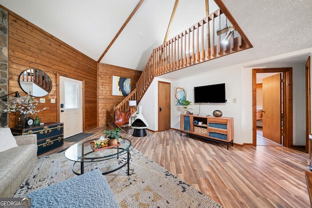 living room featuring lofted ceiling, wooden walls, a textured ceiling, and hardwood / wood-style flooring