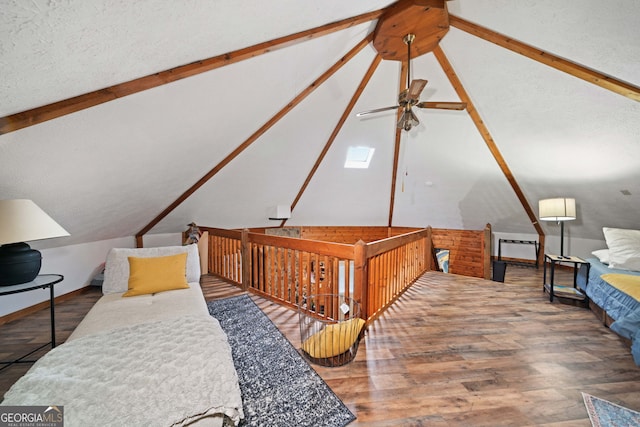 bedroom with a textured ceiling, vaulted ceiling with beams, and hardwood / wood-style flooring