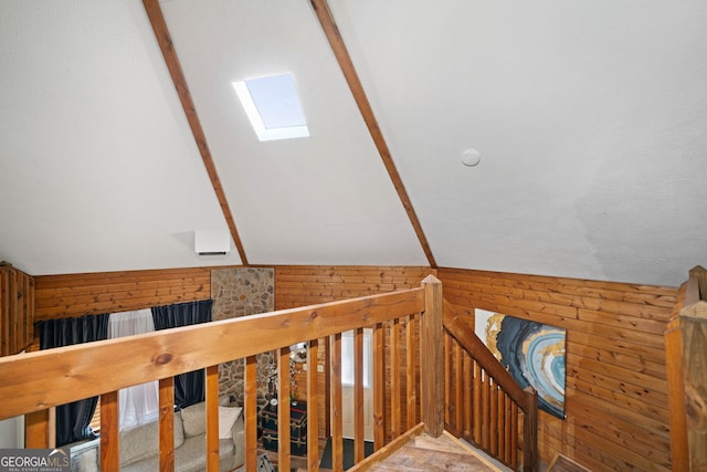 stairs with lofted ceiling with skylight and wooden walls