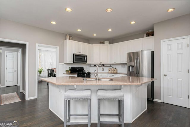 kitchen with white cabinets, a center island with sink, appliances with stainless steel finishes, and sink