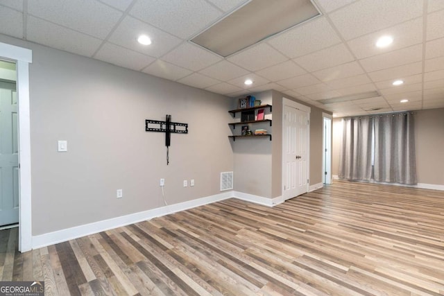 basement featuring light wood-type flooring and a drop ceiling