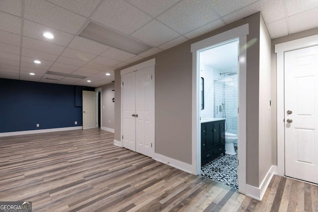 basement with hardwood / wood-style flooring and a paneled ceiling