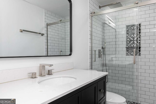 bathroom with toilet, a shower with shower door, and vanity